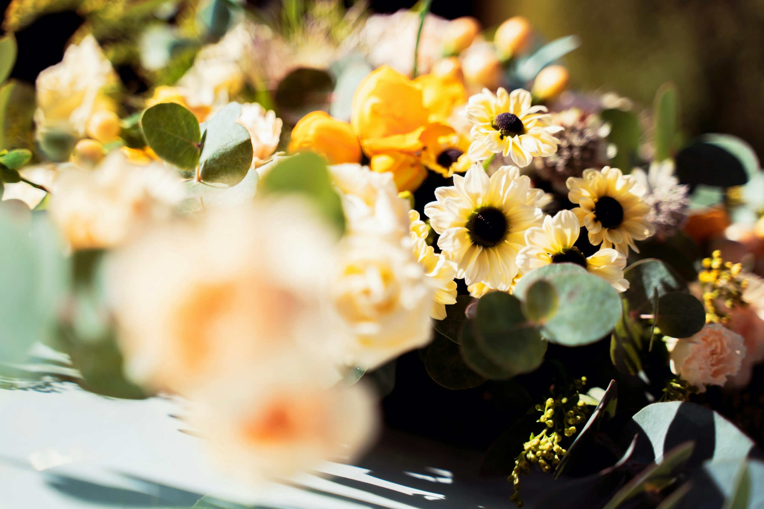 Bright bouquet showcasing yellow and white daisies with lush greenery.