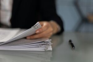 Close-up of a professional organizing a stack of documents on a desk.